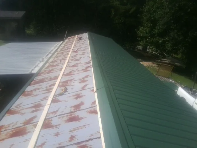 Old rusted panels beside newly installed green metal roofing — Wind Damage Roof Repair by Roofing Brothers in Fresno